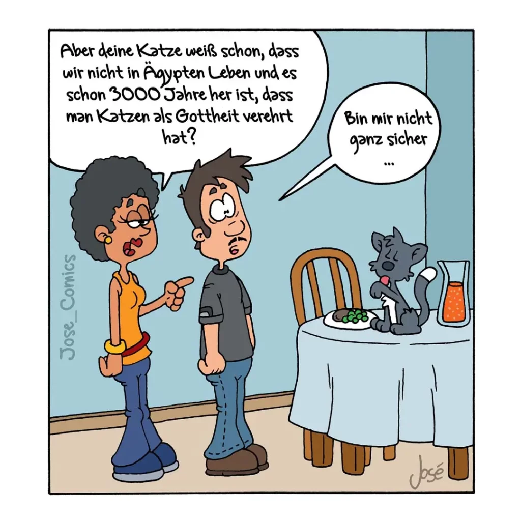 Frau erklärt Mann die ägyptische Katzengottheit, während eine graue Katze am Tisch sitzt und den Mann skeptisch anschaut