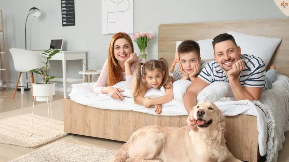 Familienhund zuhause mit Eltern und Kindern auf Bett