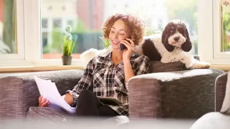 Frau sitzt mit ihrem Hund auf dem Sofa und telefoniert mit Hundehaftpflichtversicherung