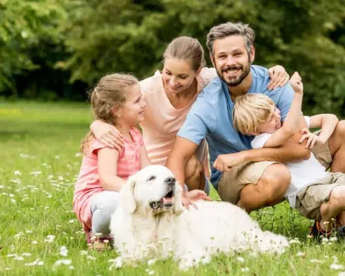 Junge Familie mit Golden Retriever glücklich im Garten, Interaktion mit Hunden tut Menschen nachweislich gut
