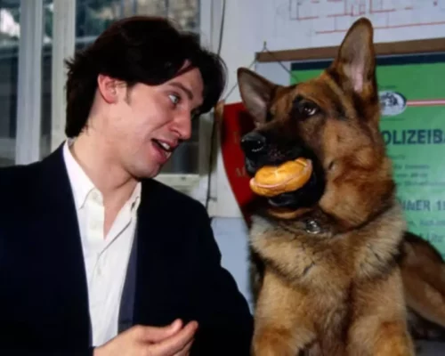 Schauspieler Tobias Moretti mit Polizeihund Kommissar Rex Wurstsemmel im Maul Fernsehserie