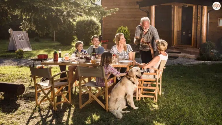 Familienhund beim gemeinsamen Essen draussen im Garten, Ferienhaus Holzhaus im Hintergrund